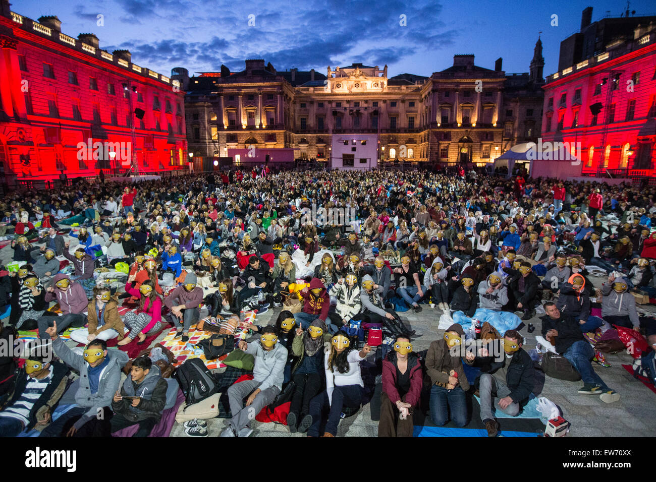 Crowd of people wearing monkey masks at Somerset House, in London, lit ...