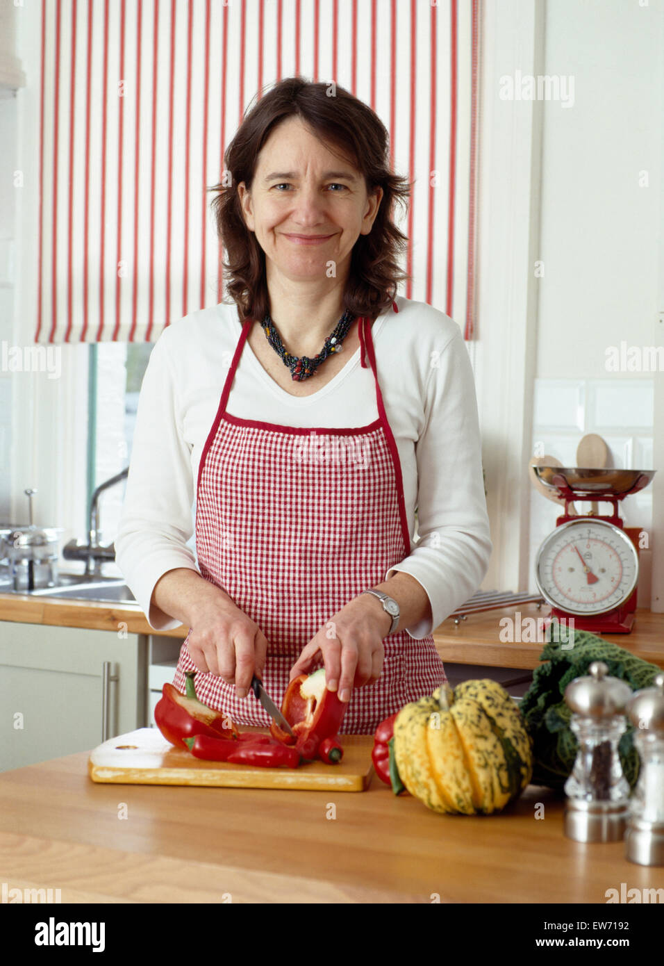 Portrait of smiling woman chopping up red peppers         FOR EDITORIAL USE ONLY Stock Photo
