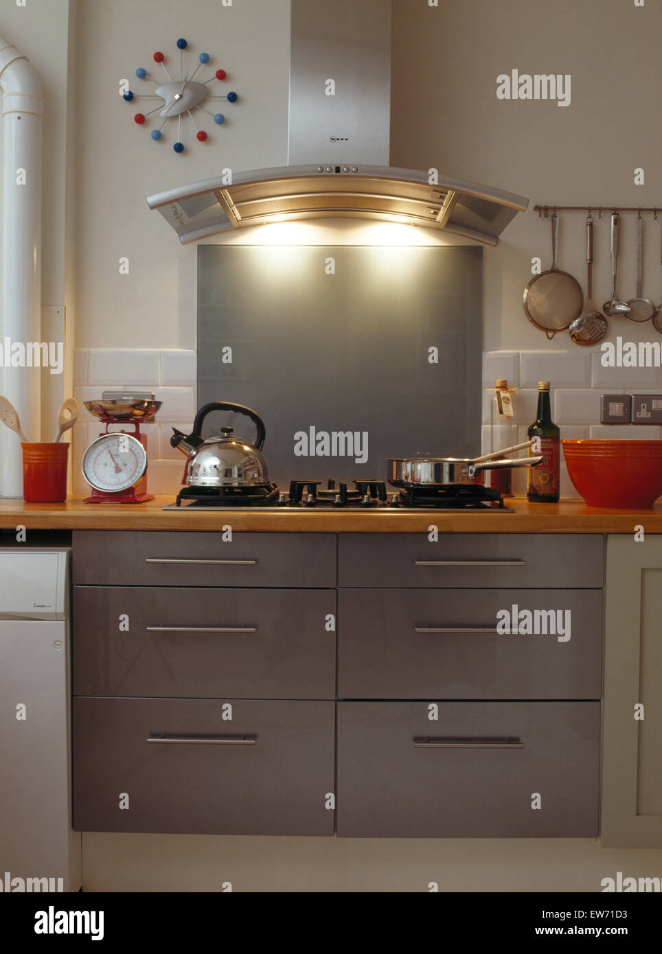 Integral lighting on stainless steel extractor above hob with steel kettle and pans Stock Photo