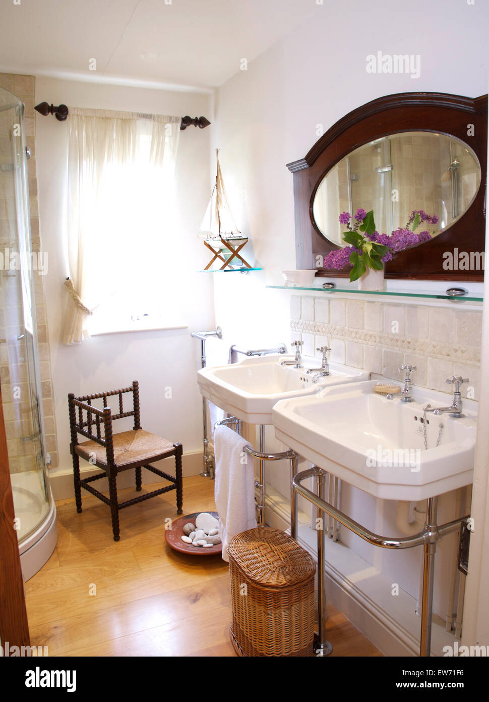 Antique mirror above double basins in a traditional white bathroom with ...