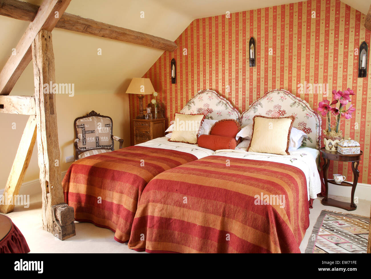 Terracotta striped bed covers on upholstered twin beds in attic bedroom