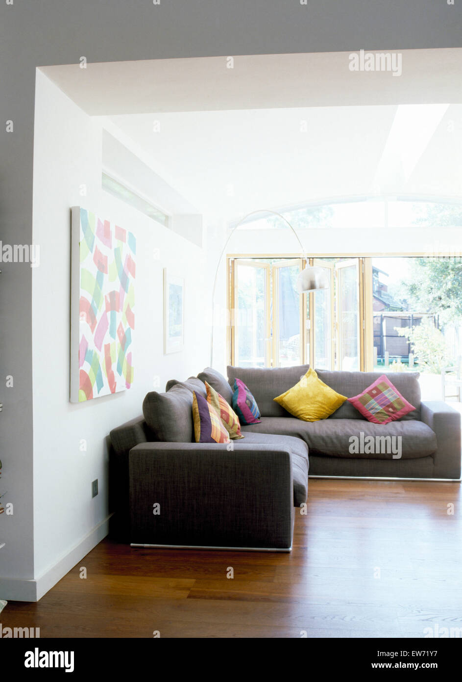 Colorful cushions on gray angular sofas in modern living room with