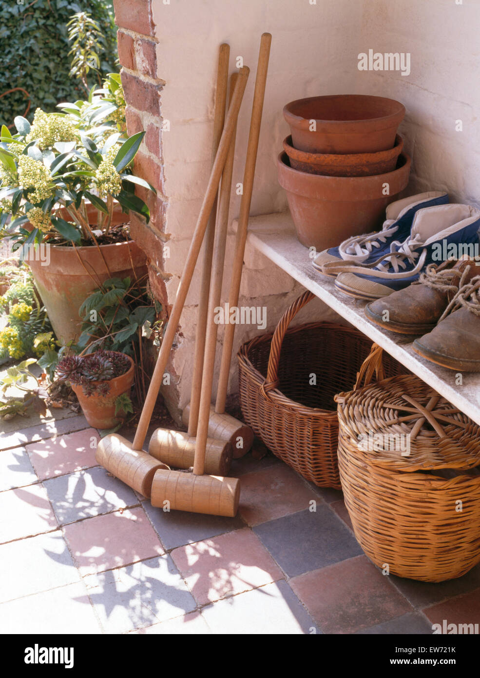 Close-up of wooden croquet mallets in porch with boots and baskets Stock Photo