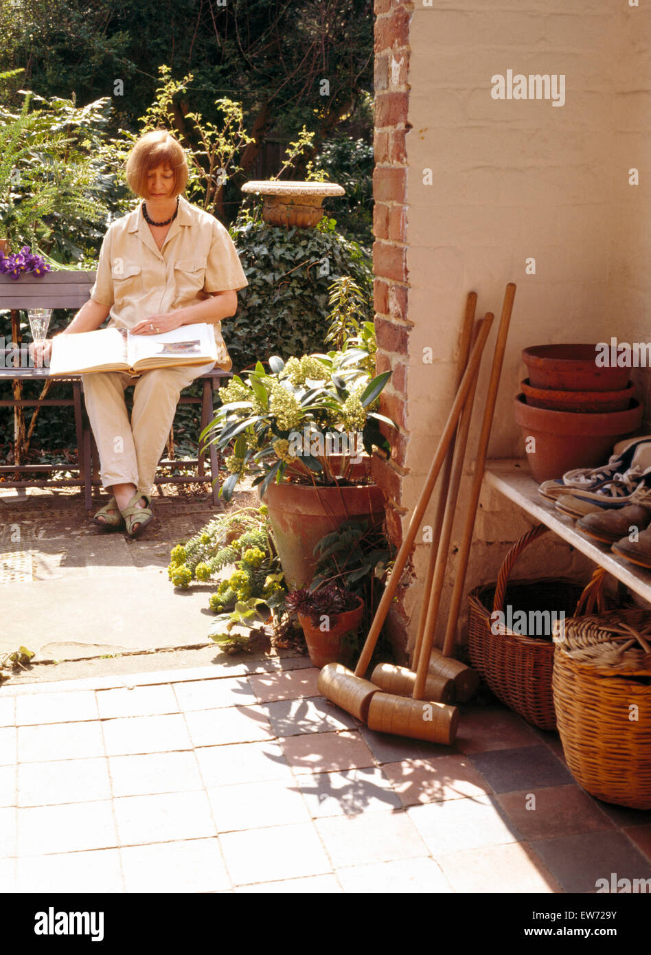 Woman sitting and reading on garden bench Stock Photo - Alamy