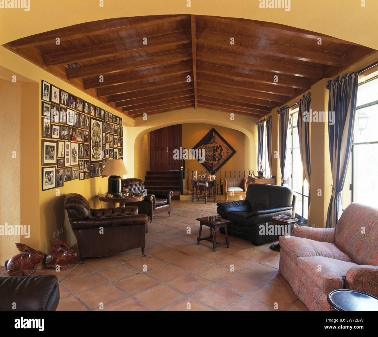 Terracotta tiled floor in yellow living room of Spanish villa with leather armchairs Stock Photo