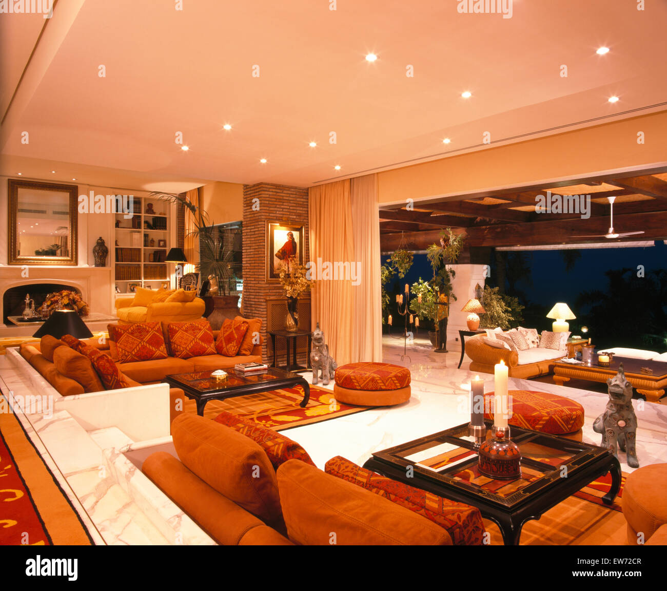 Orange sofas and rugs in living room in large Spanish villa with open doors to the terrace Stock Photo