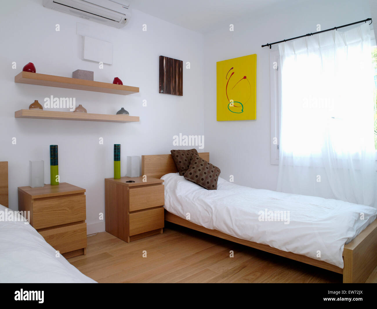Simple wood shelves above bedside tables beside single beds with white