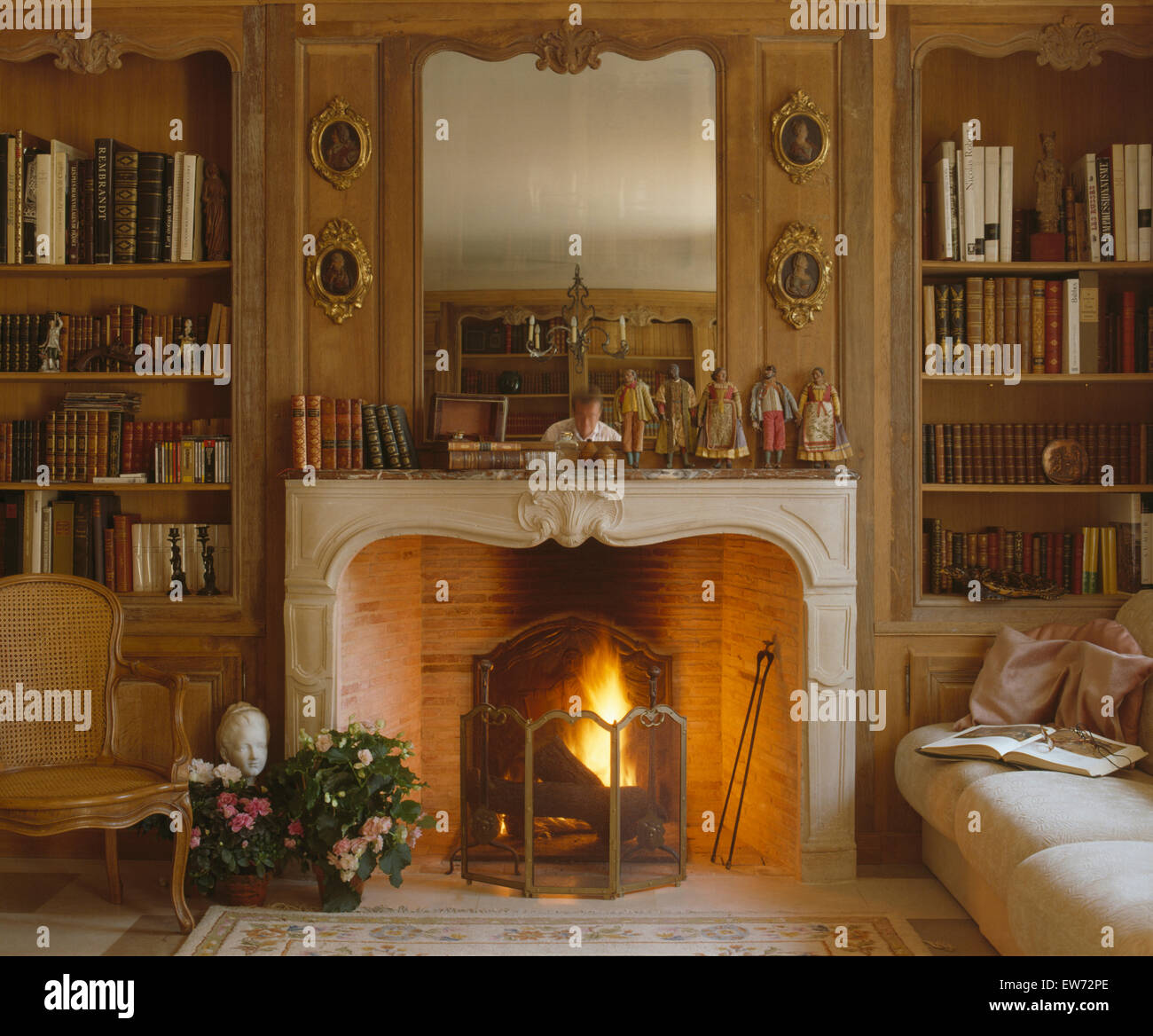 Mirror above fireplace with lighted fire in very traditional French living room Stock Photo Alamy
