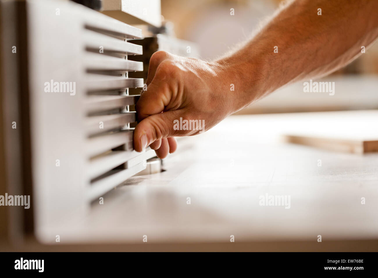robust hands of a man working on a wood shaper (spindle moulder) in a carpenter workshop, detail of the hand adjusting the machi Stock Photo