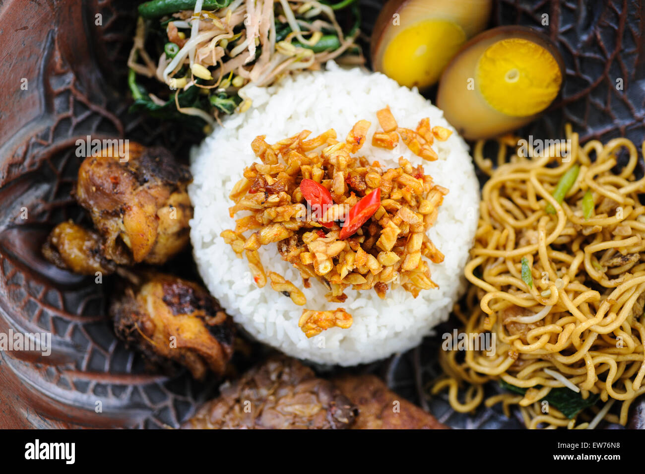 Indonesian nasi campur with fried chicken, noodles, eggs, tempeh and vegetables. Stock Photo