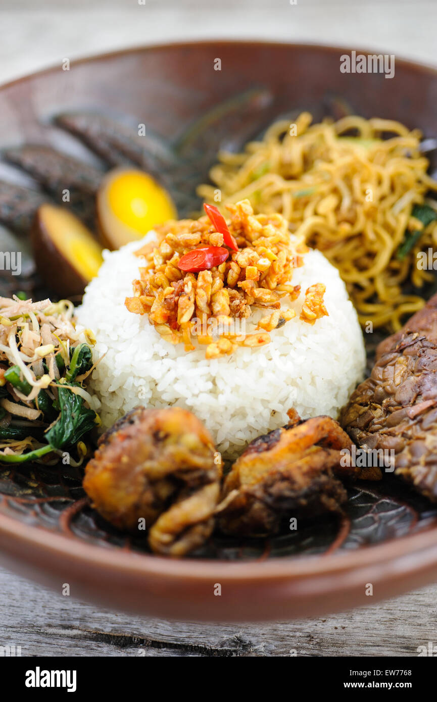 Indonesian nasi campur with fried chicken, noodles, eggs, tempeh and vegetables. Stock Photo