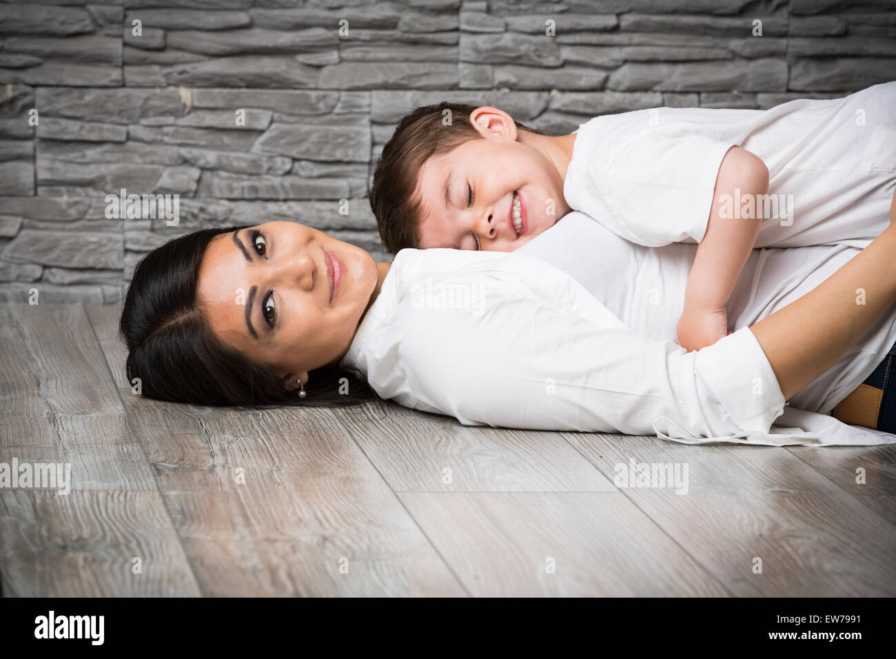 Mother and son cuddling on the floor Stock Photo