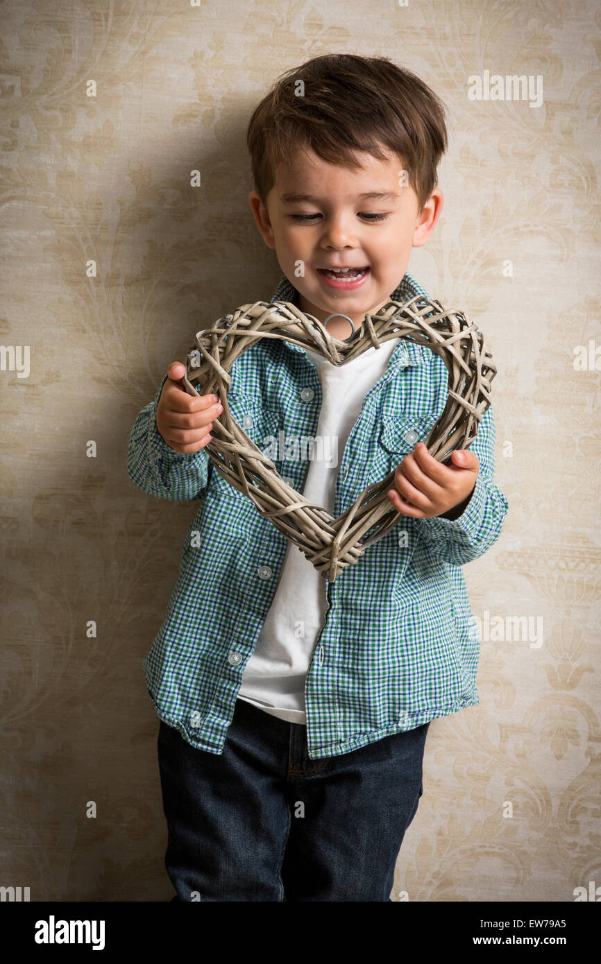 Little boy holding a wooden heart in his hand Stock Photo