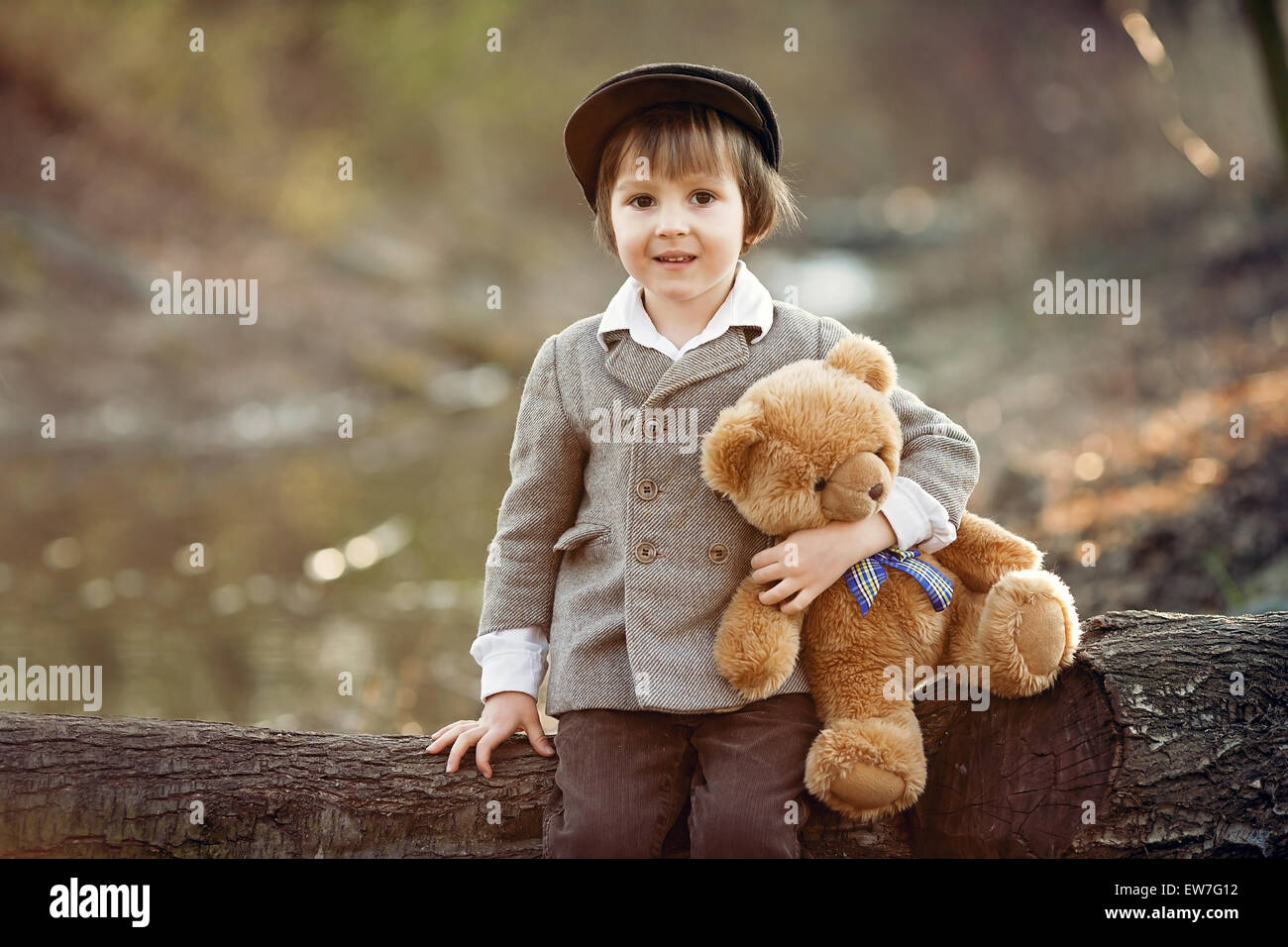 Adorable little boy with his teddy bear friend in the park on sunset ...