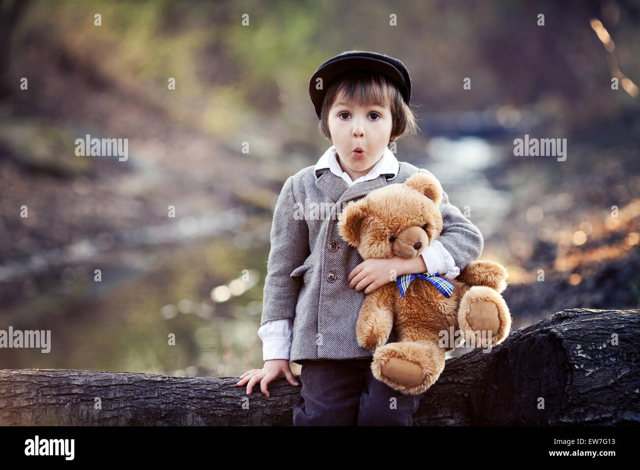 Adorable little boy with his teddy bear friend in the park on sunset ...