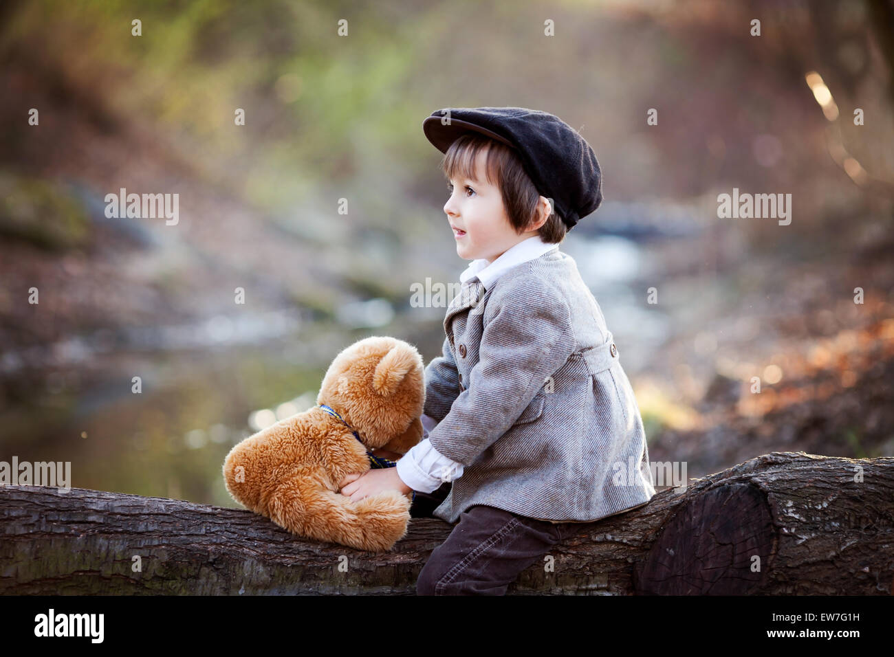 Adorable little boy with his teddy bear friend in the park on sunset ...