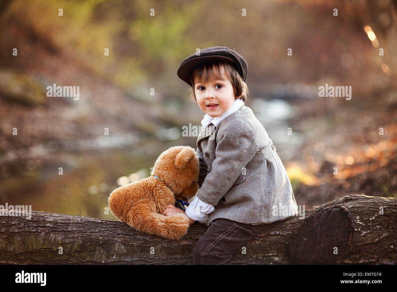 Adorable little boy with his teddy bear friend in the park on sunset ...