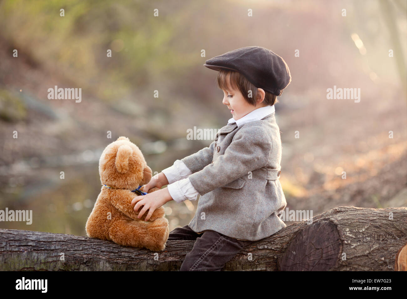 Adorable little boy with his teddy bear friend in the park on sunset ...