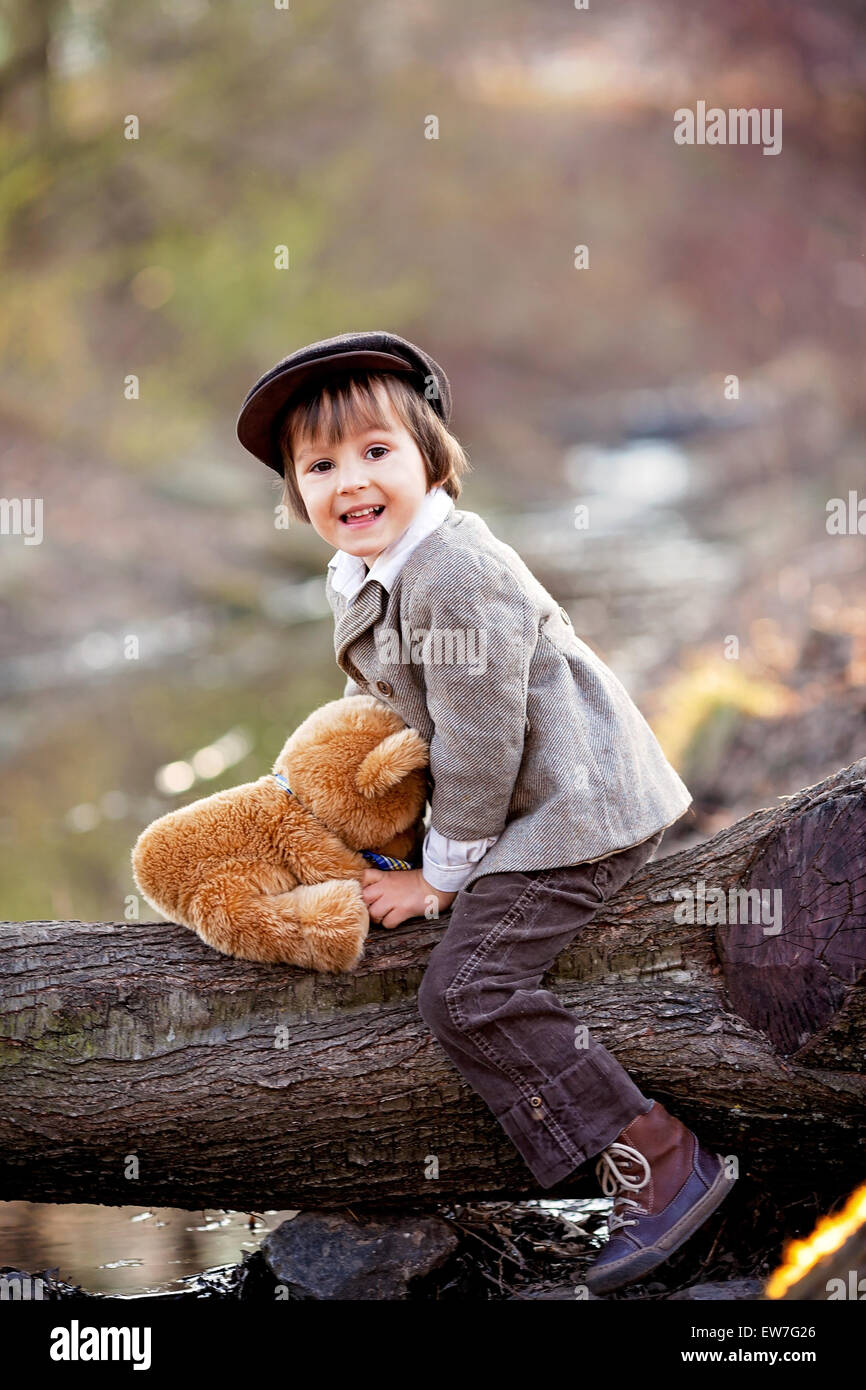 Adorable little boy with his teddy bear friend in the park on sunset ...