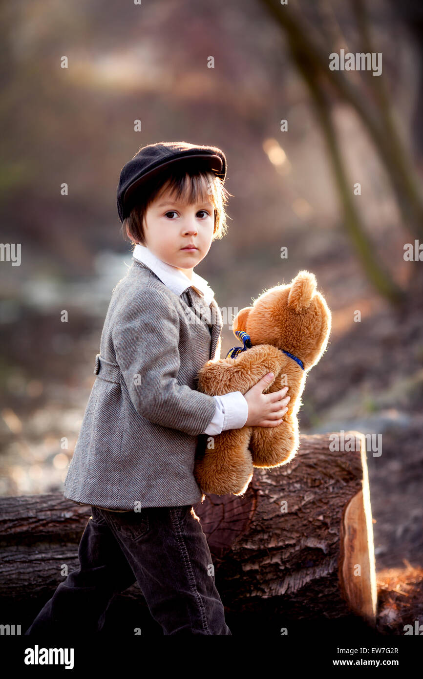 Adorable little boy with his teddy bear friend in the park on sunset ...