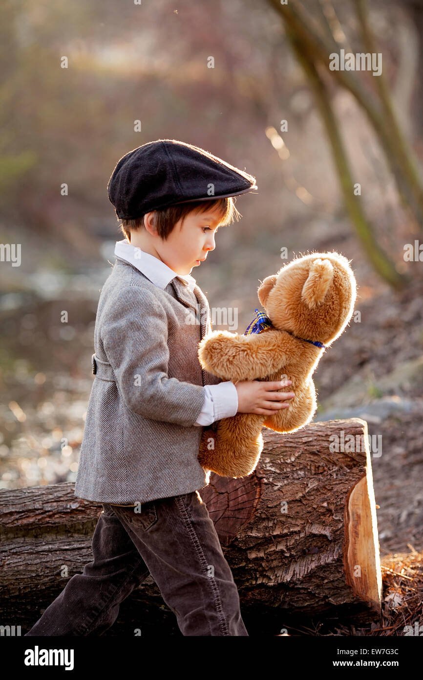 Adorable little boy with his teddy bear friend in the park on sunset ...