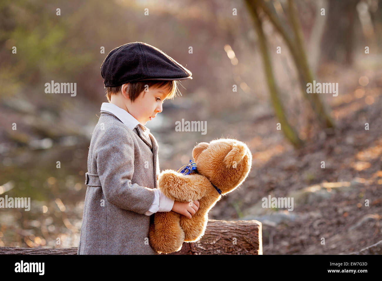 Adorable little boy with his teddy bear friend in the park on sunset ...