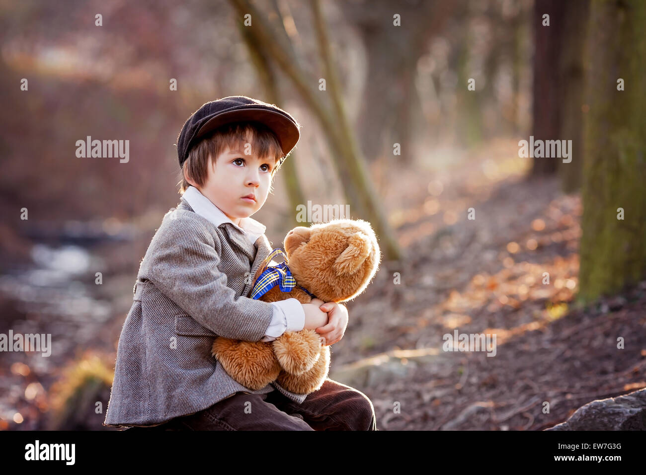 Adorable little boy with his teddy bear friend in the park on sunset ...