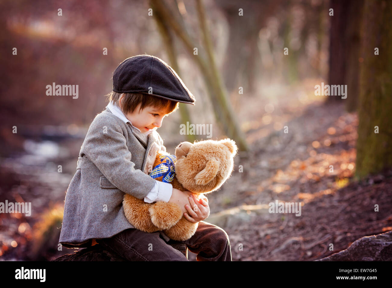 Adorable little boy with his teddy bear friend in the park on sunset ...