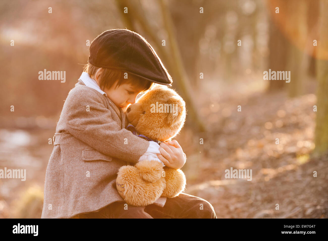 Adorable little boy with his teddy bear friend in the park on sunset ...