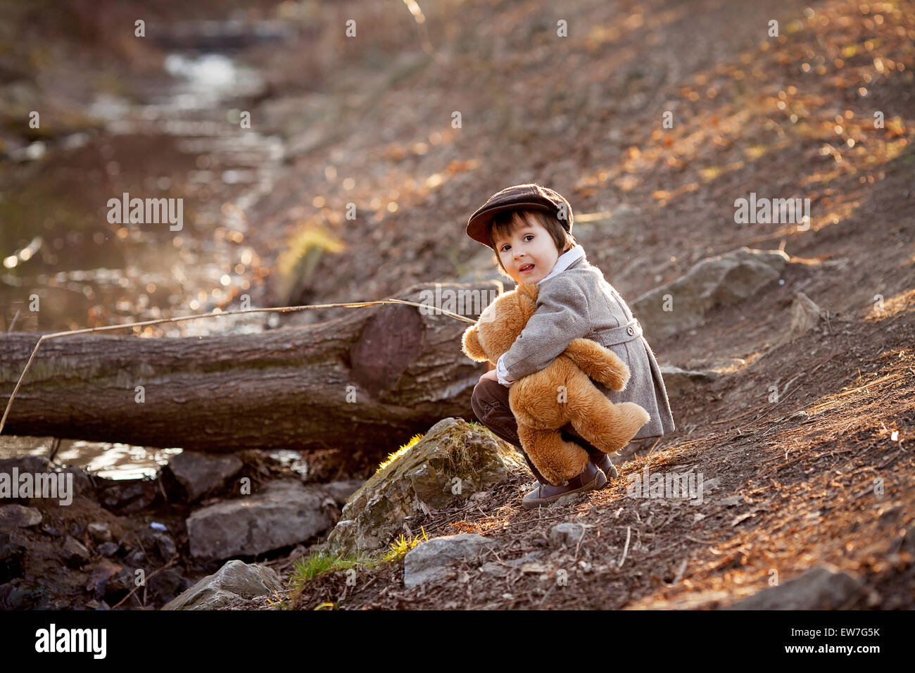 Adorable little boy with his teddy bear friend in the park on sunset ...