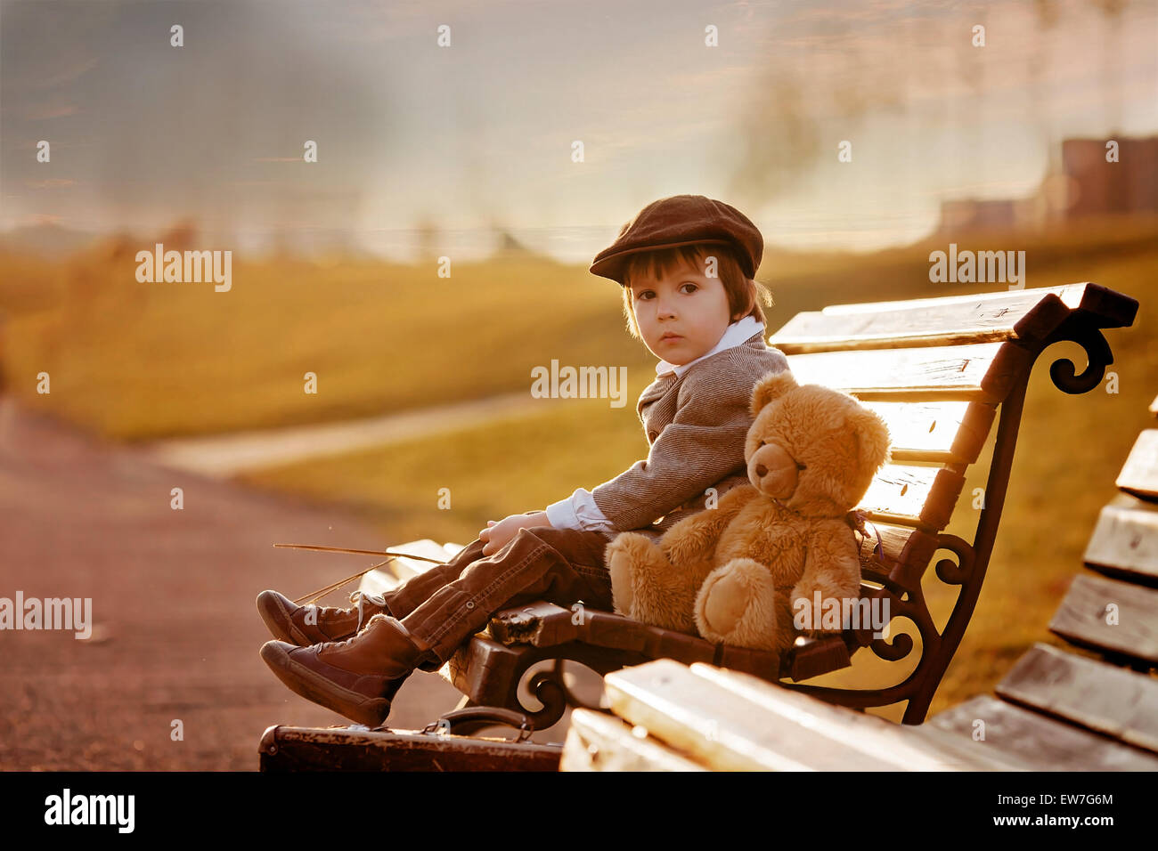 Adorable little boy with his teddy bear friend in the park on sunset ...