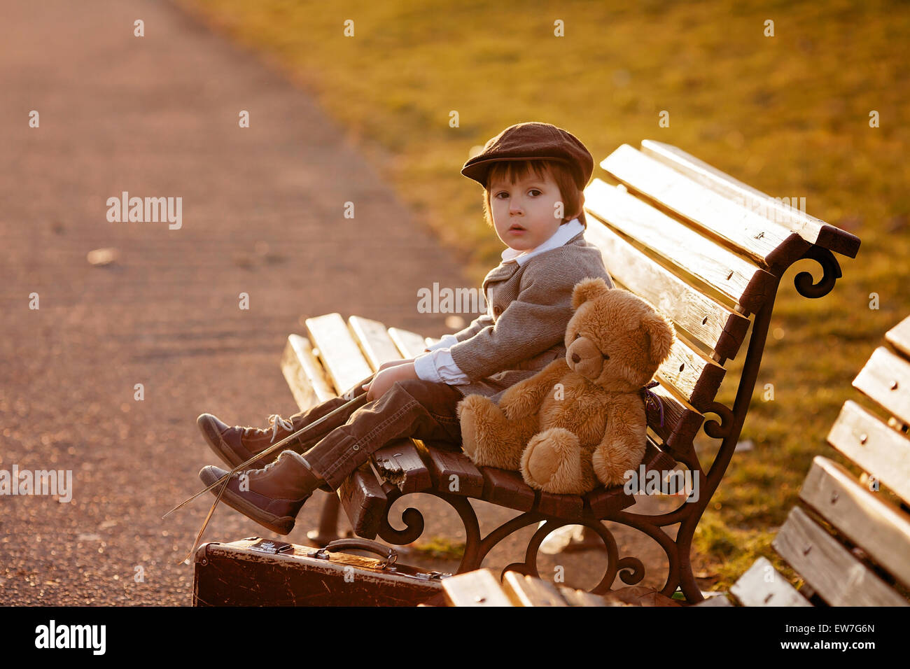 Adorable little boy with his teddy bear friend in the park on sunset ...