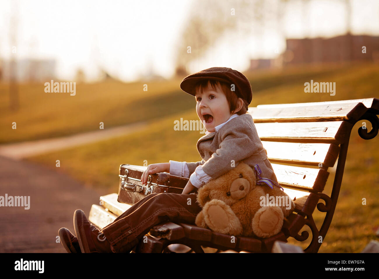 Adorable little boy with his teddy bear friend in the park on sunset ...