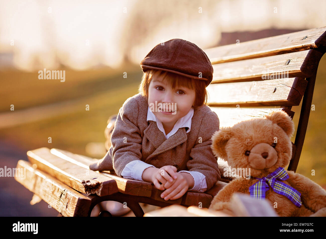 Adorable little boy with his teddy bear friend in the park on sunset ...