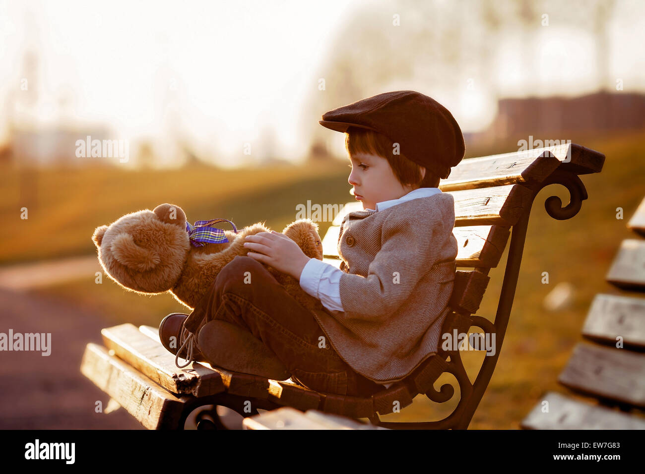Adorable little boy with his teddy bear friend in the park on sunset ...