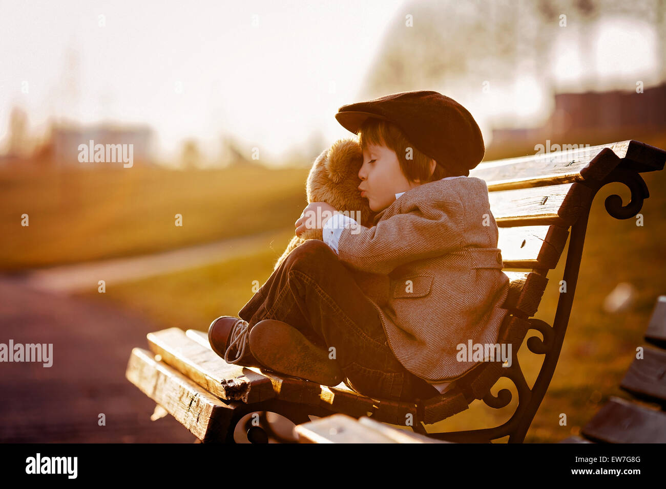 Adorable little boy with his teddy bear friend in the park on sunset ...