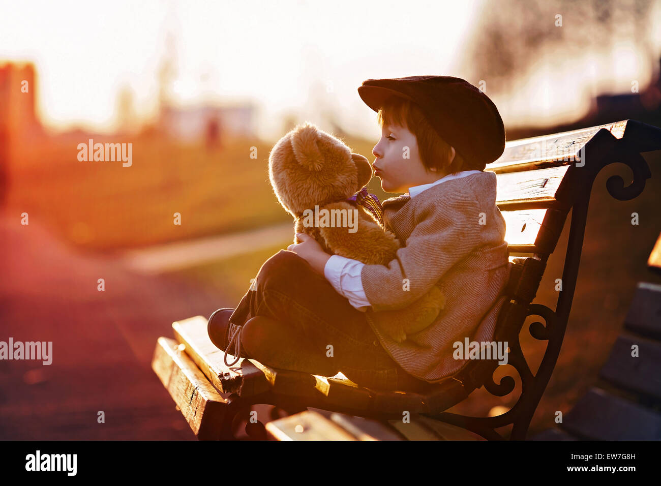 Adorable little boy with his teddy bear friend in the park on sunset ...