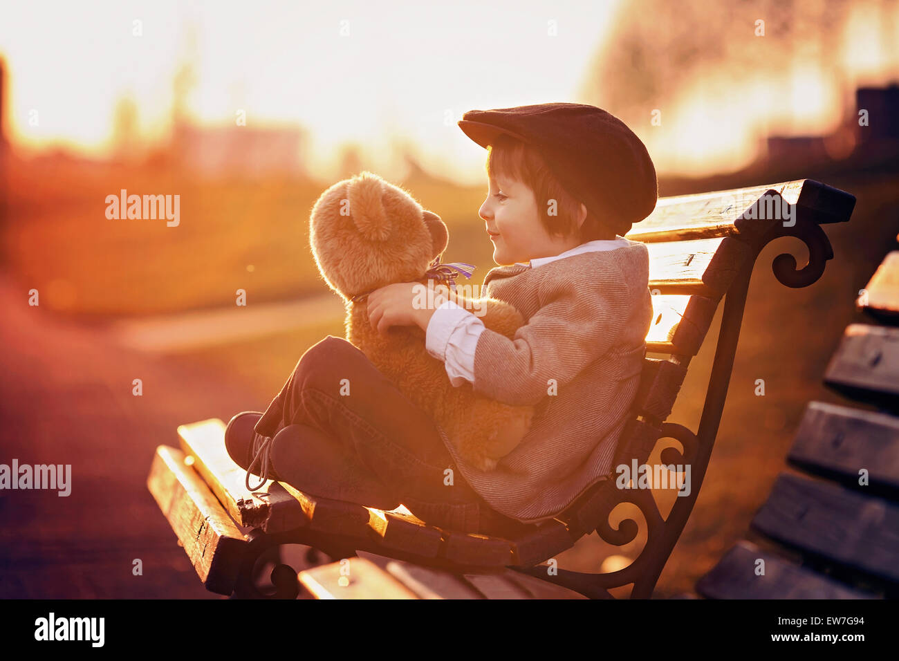 Adorable little boy with his teddy bear friend in the park on sunset ...