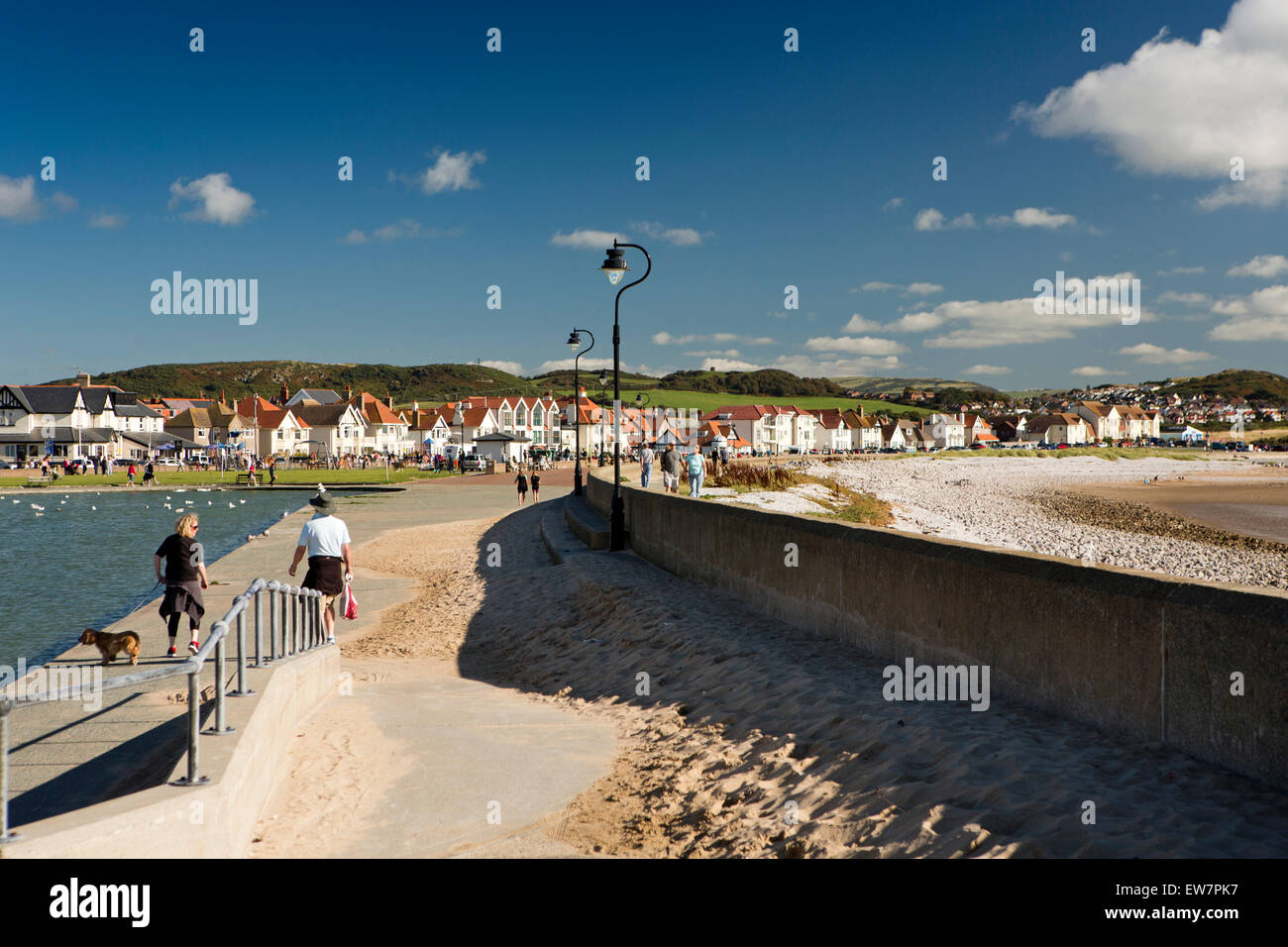 UK, Wales, Conwy, Llandudno, West Shore, people walking dog past paddling pool Stock Photo