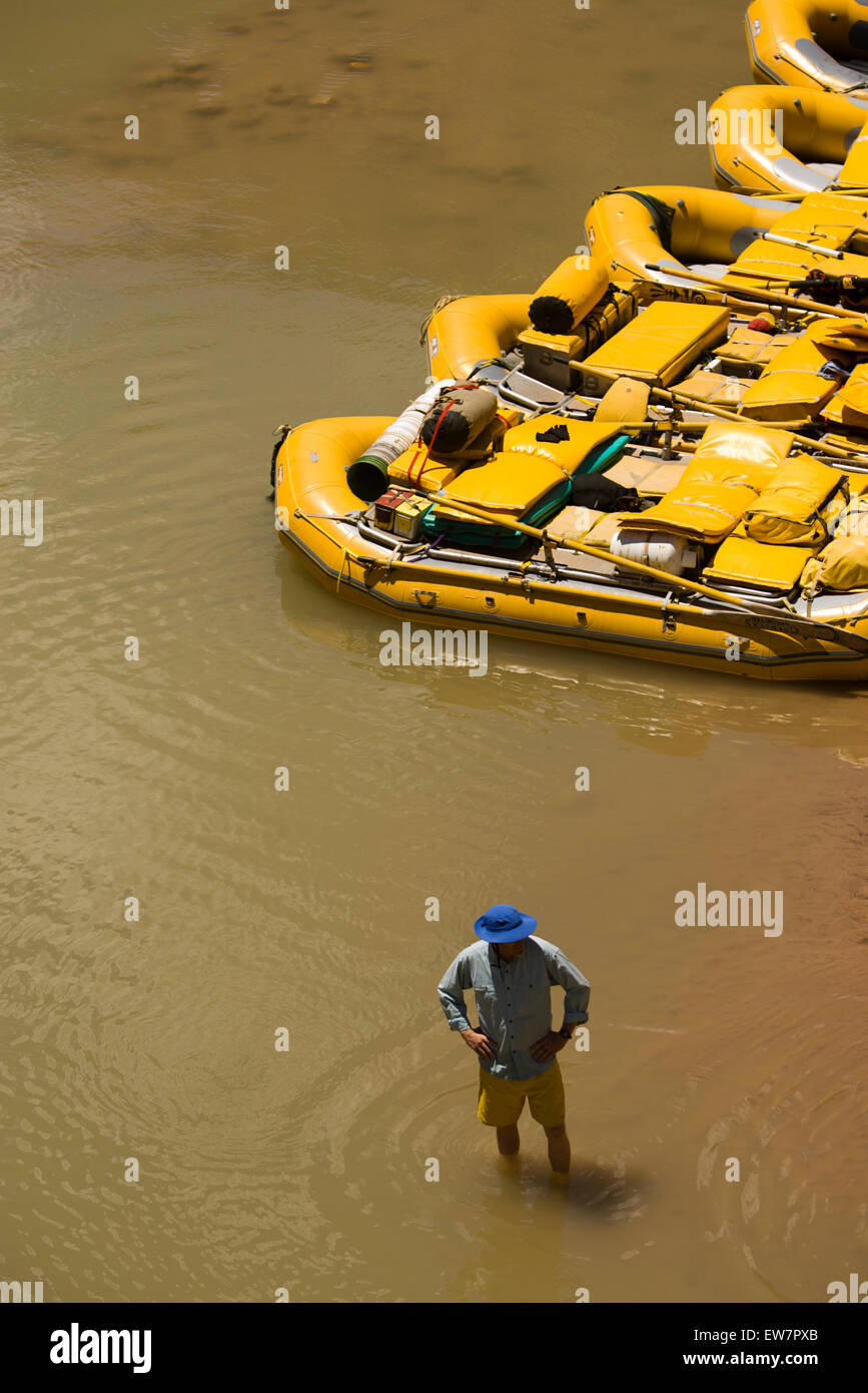 High angle perspective of a man wading in the water next to a raft down ...