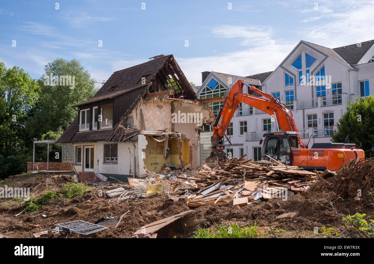Partially demolished house with construction debris and digger Stock Photo