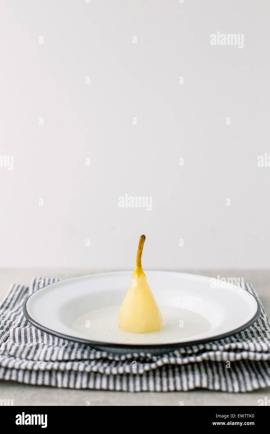 Poached pear in vanilla syrup on a plate Stock Photo