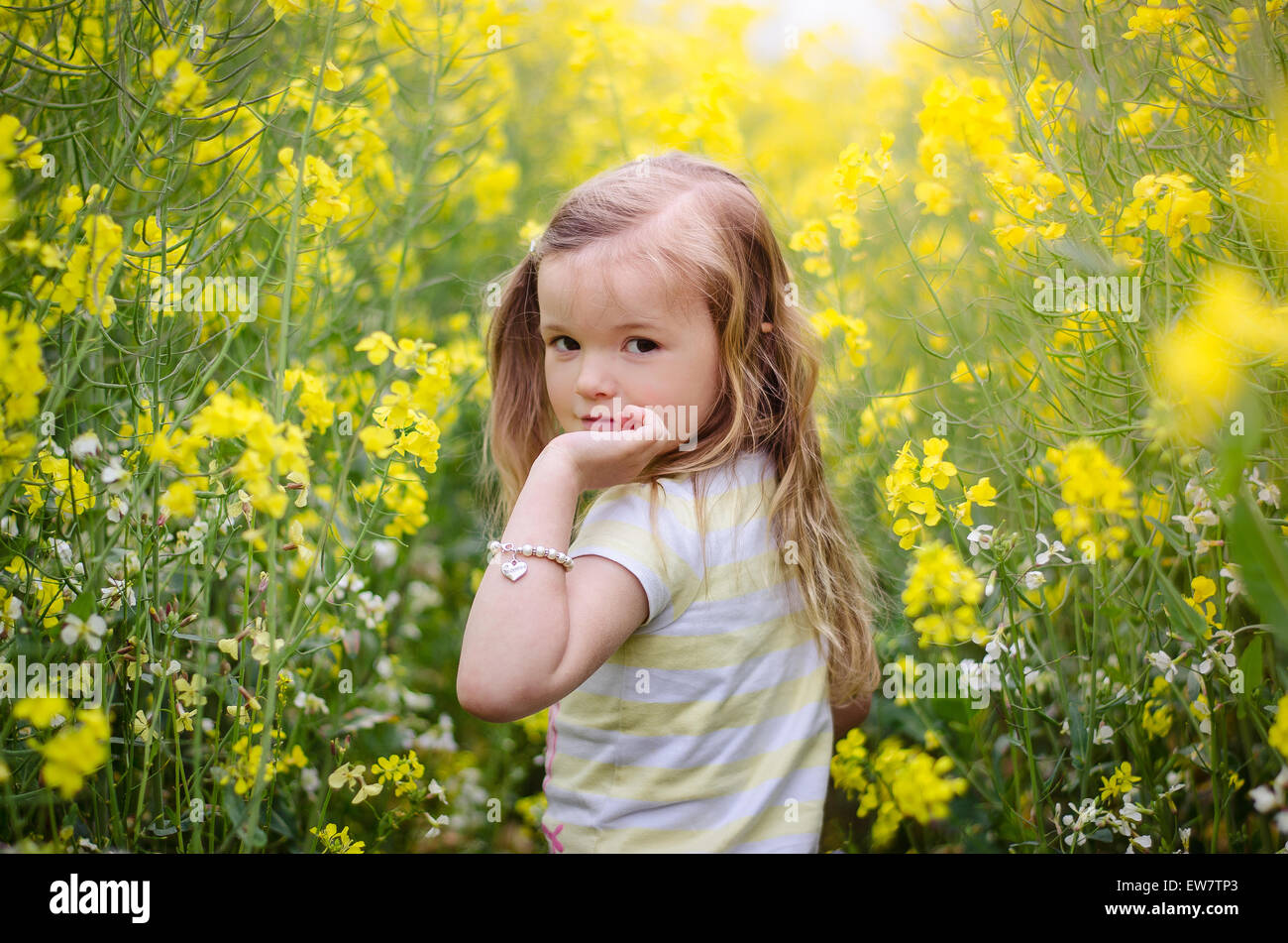 Girl looking over her shoulder in a meadow of yellow flowers Stock Photo
