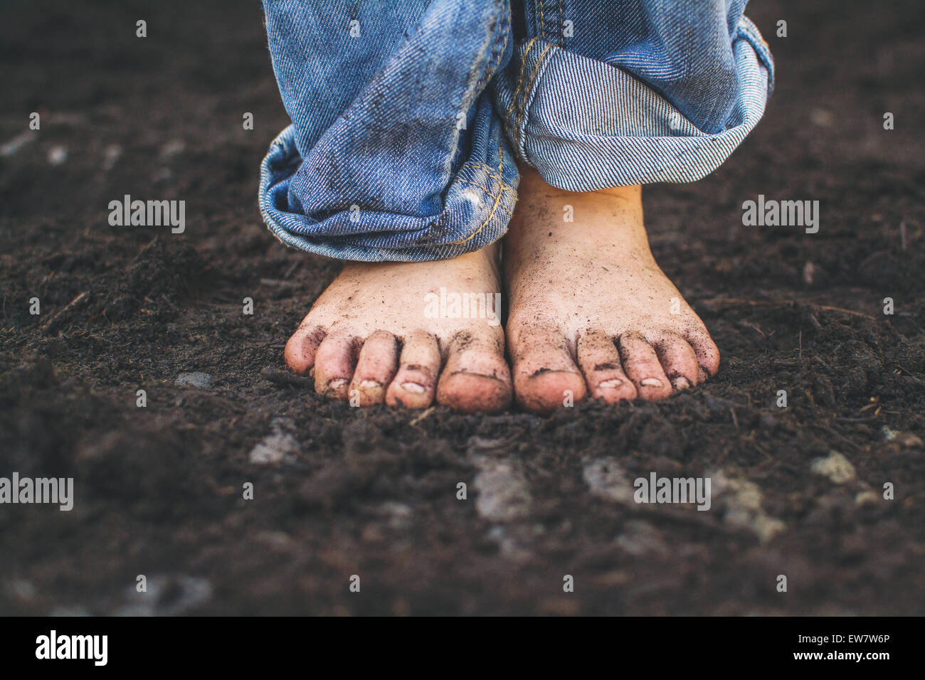 Close-up of a boy's dirty feet standing in soil Stock Photo