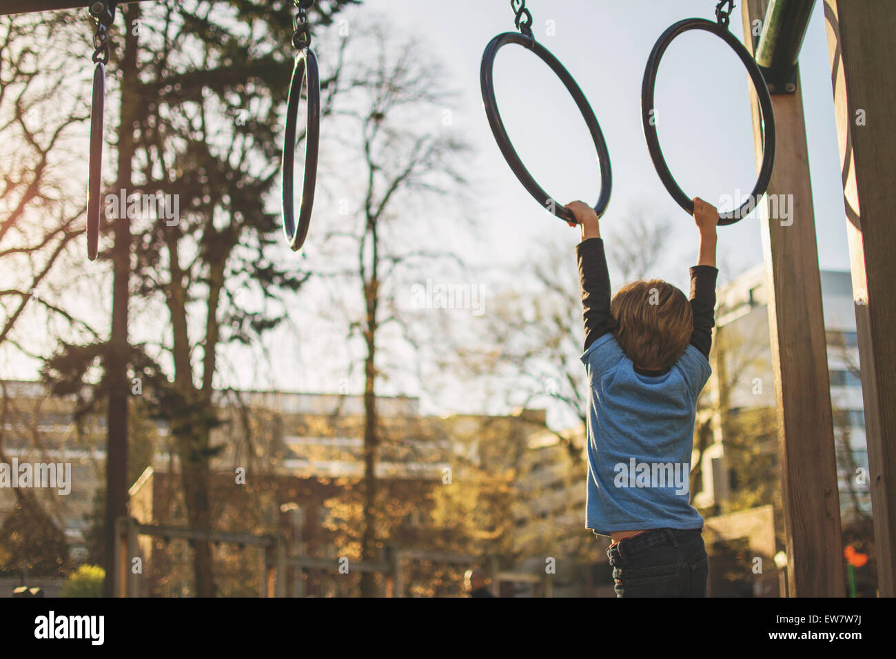 Boy hanging from rings at playground, USA Stock Photo