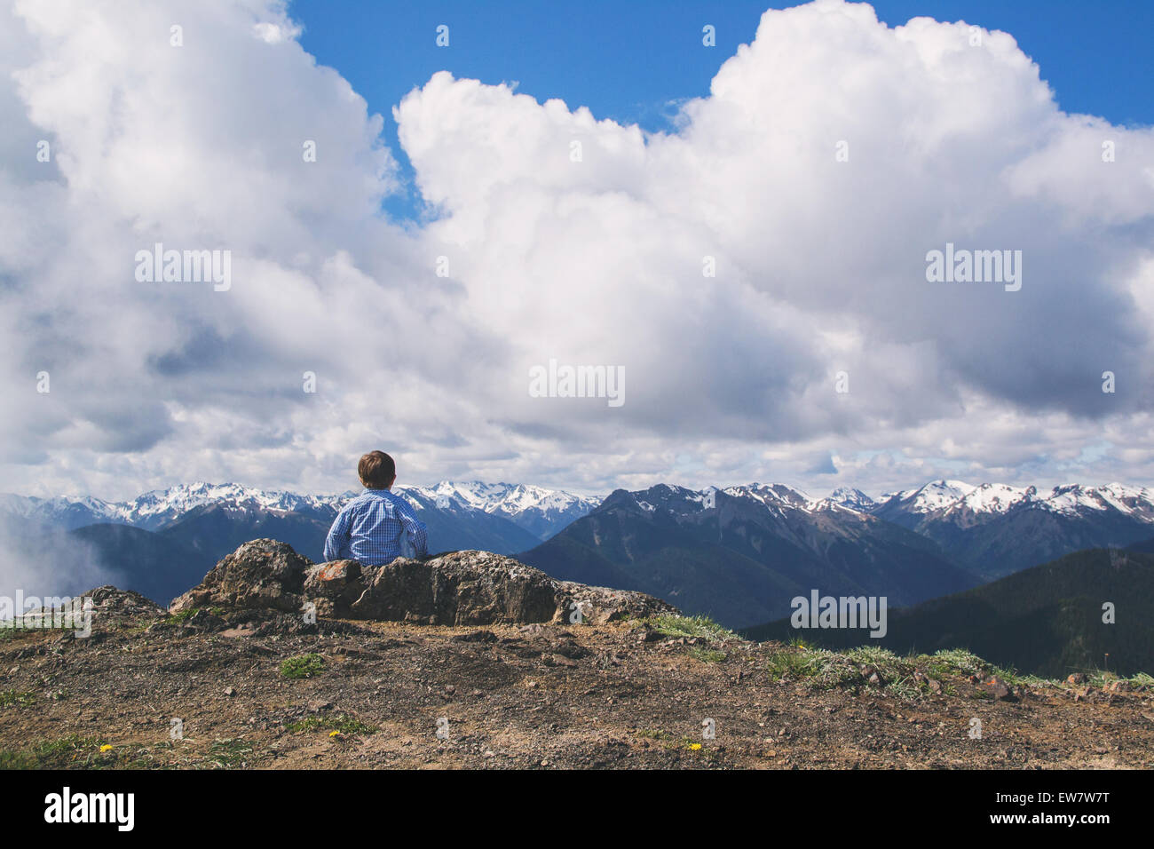 Rear view of a boy sitting on mountain looking at view, USA Stock Photo ...