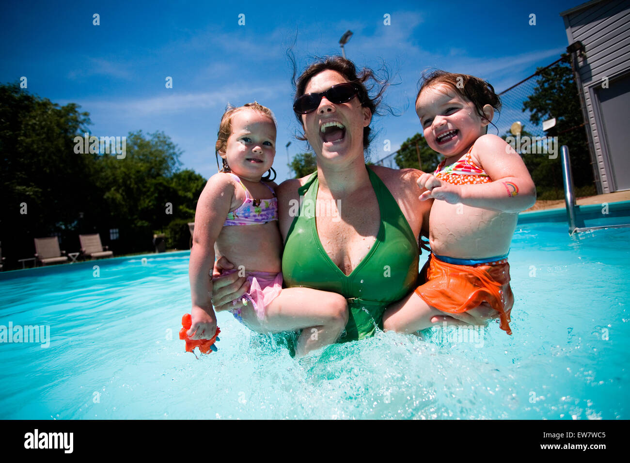 Two small girls swim with mom. Stock Photo