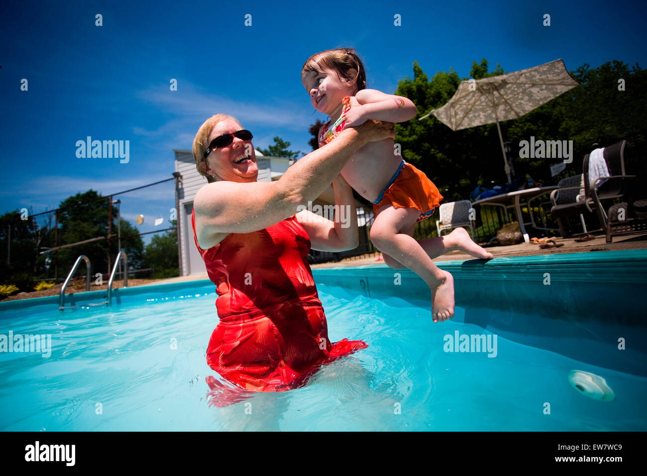 A small girl jumps into the pool. Stock Photo