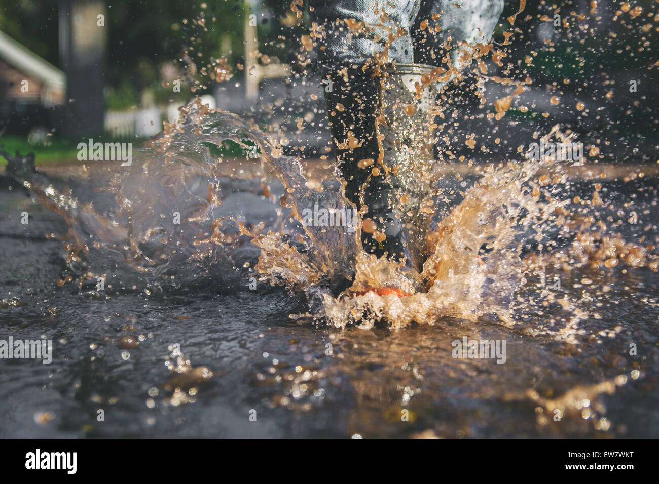 Close-up of child's legs splashing in a puddle of water Stock Photo