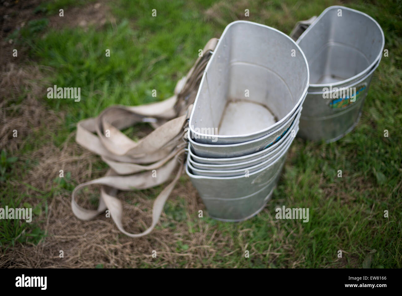 Two pile of metal fruit-picking buckets with straps placed on the ground Stock Photo